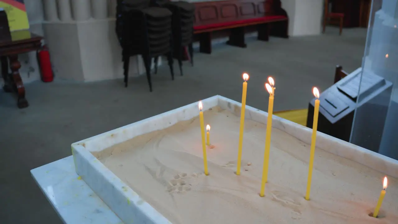 Closeup shot of the lit prayer candles for the dead in a sandbox in a Catholic Church