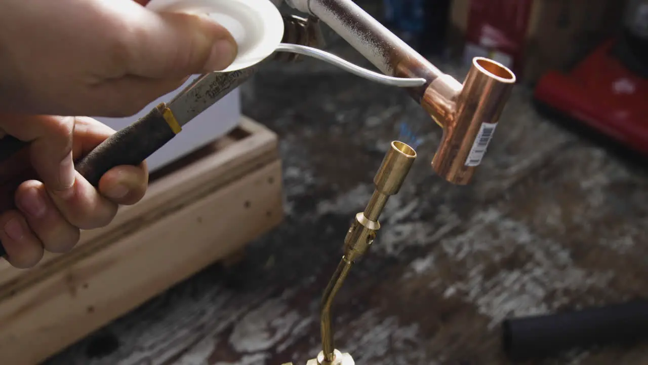 A copper tee fitting is welded to a pipe using solder a propane blow torch and an adjustable wrench