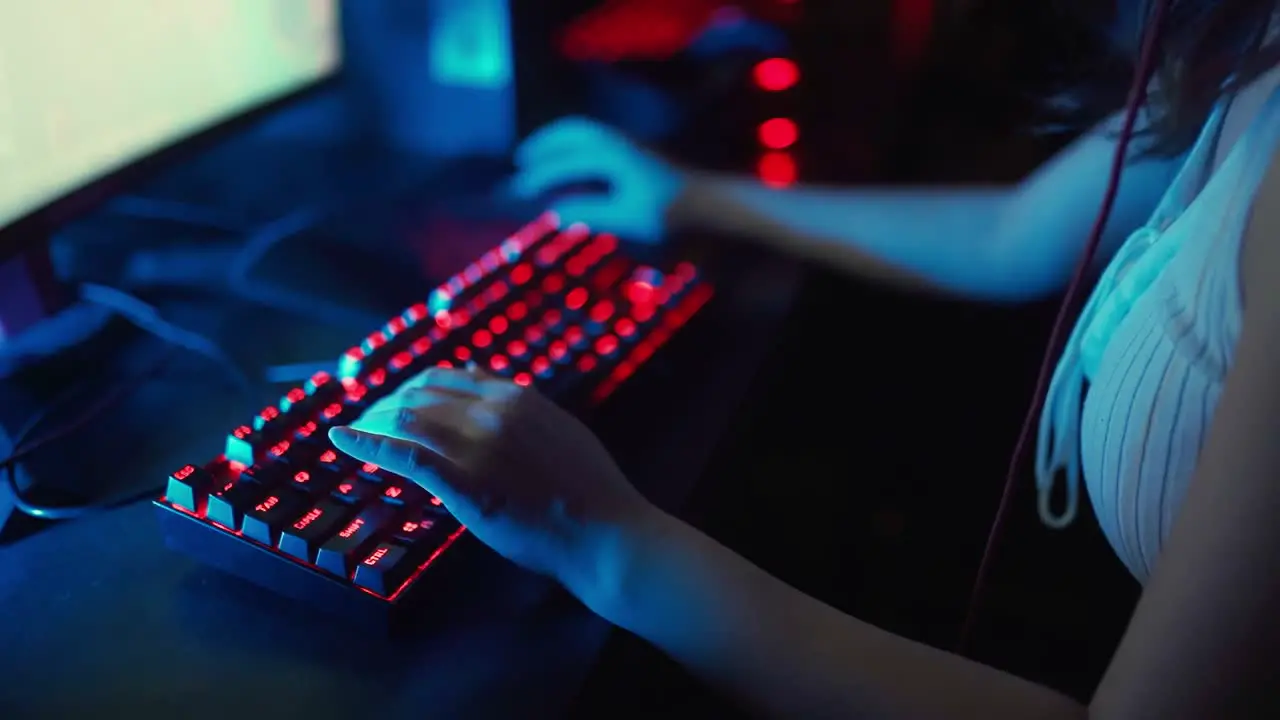 Close up of young woman while playing a video game with mouse and keyboard