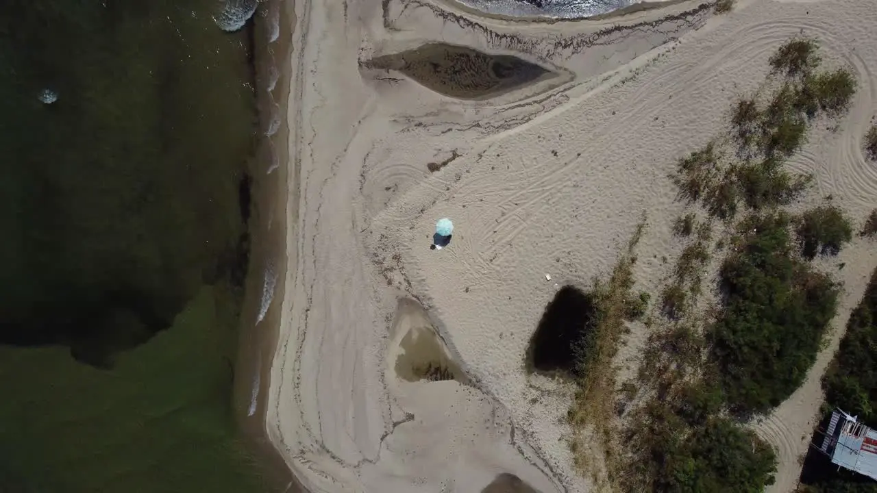 Aerial pull-up over single umbrella on beach