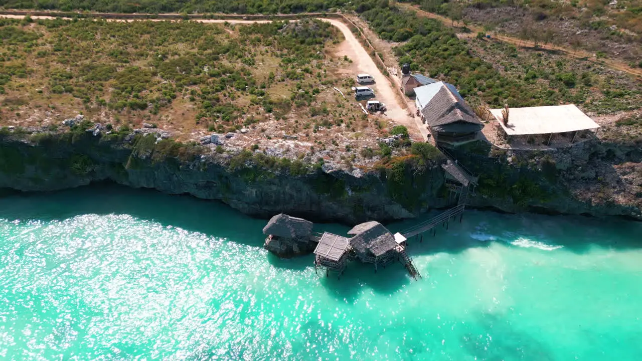 Aerial view from a drone of a restaurant perched on wooden stilts above the turquoise waters of a cliff in Zanzibar Tanzania