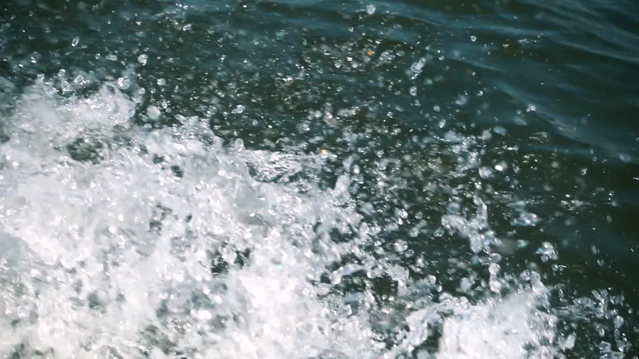 Water splashing in slow motion from a boat making its way on a lake