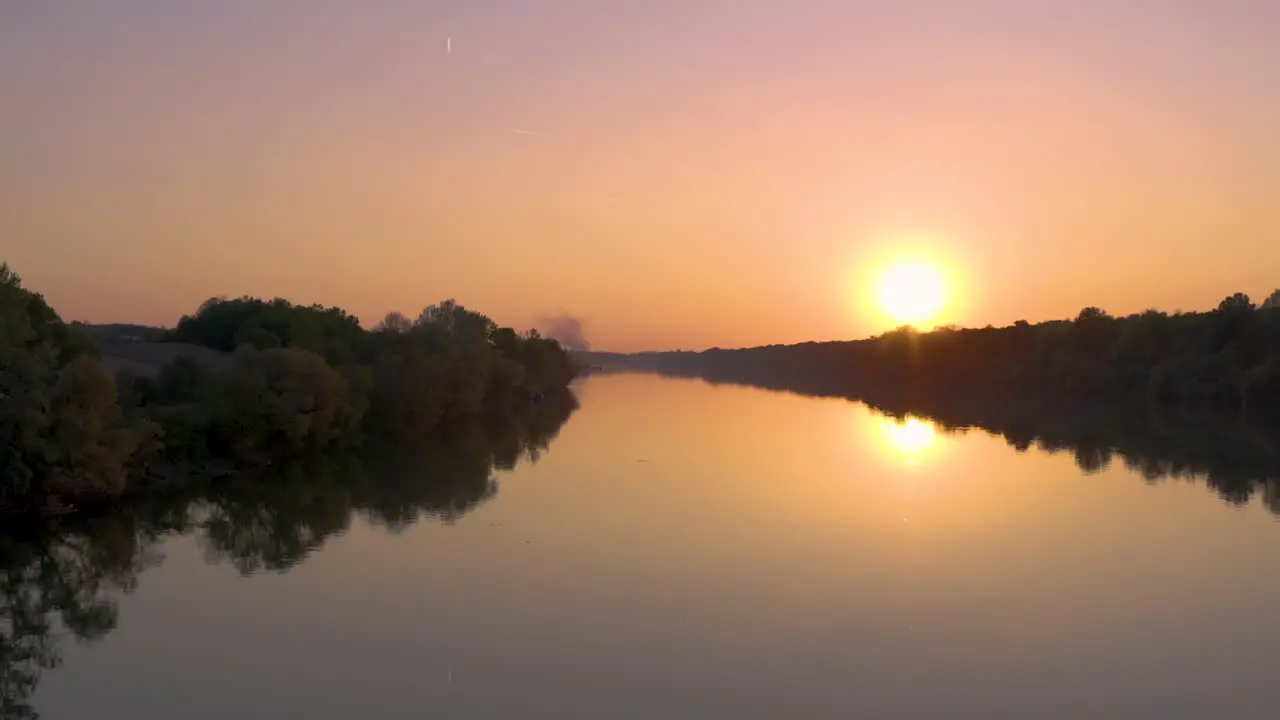 Drone footage in the sunset flying above river with beautiful forest around