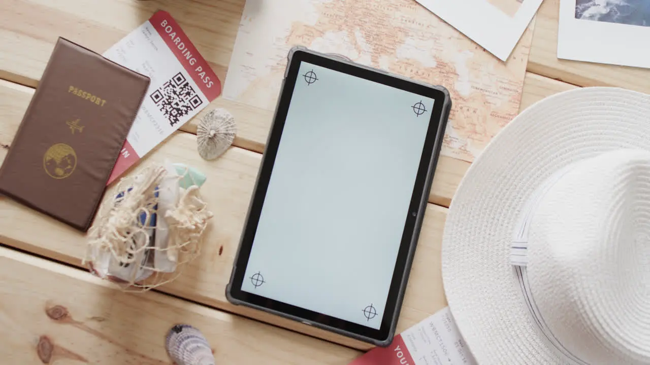 Flat lay of tablet with copy space passport and sunhat on wooden background