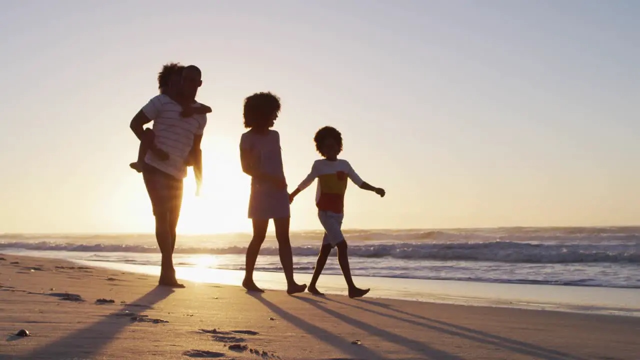 African american family having fun walking together during sunset on the beach