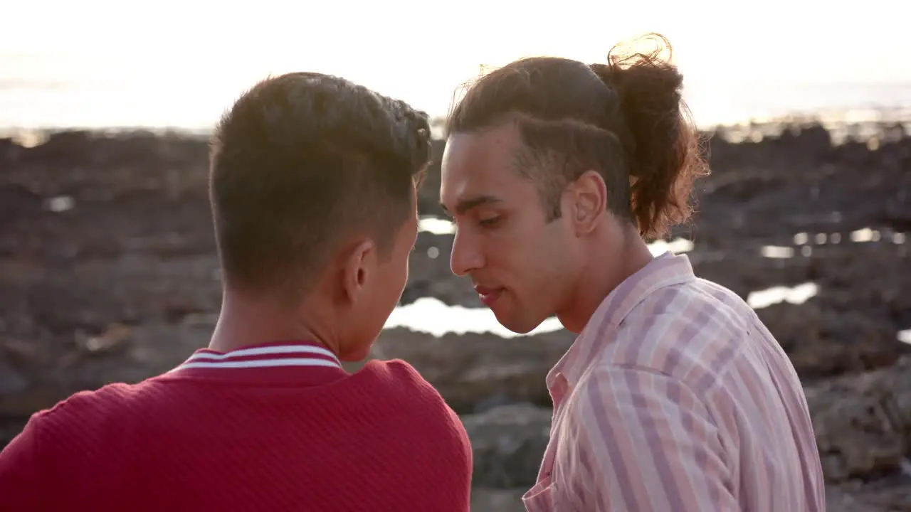 Happy diverse gay male couple embracing at beach slow motion