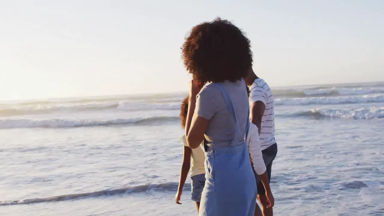 African american mother and son dancing together during sunset at the beach