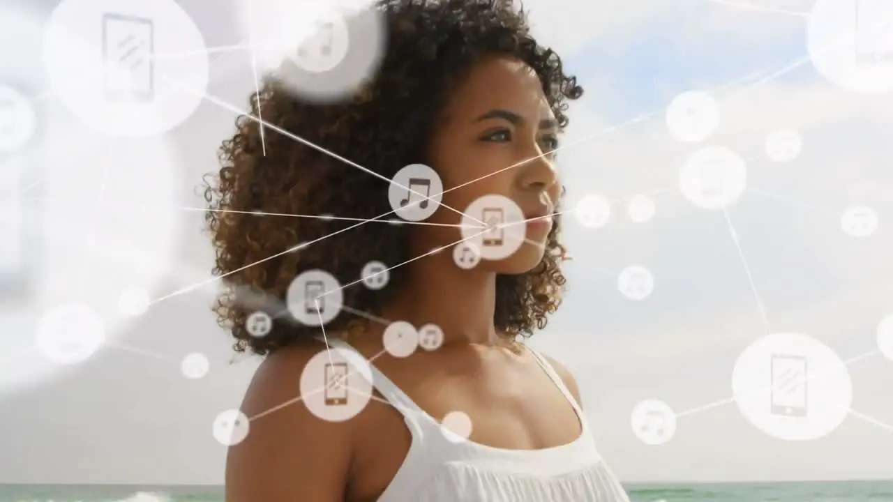 Network of digital icons against african american woman standing at the beach