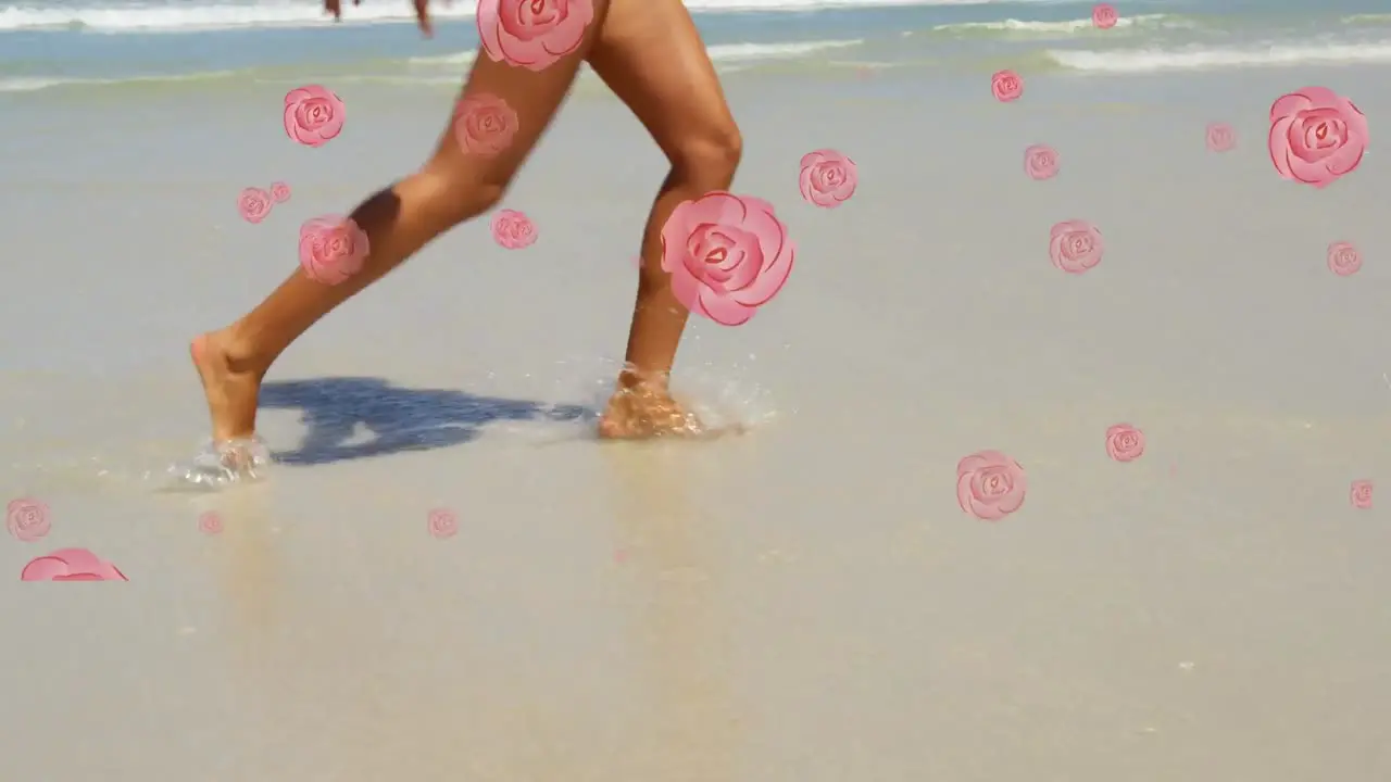 Multiple pink rose icons falling against low section of woman walking on the beach