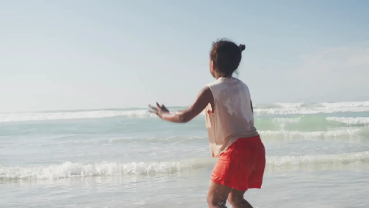 Rear view of african american girl jumping and enjoying at the beach