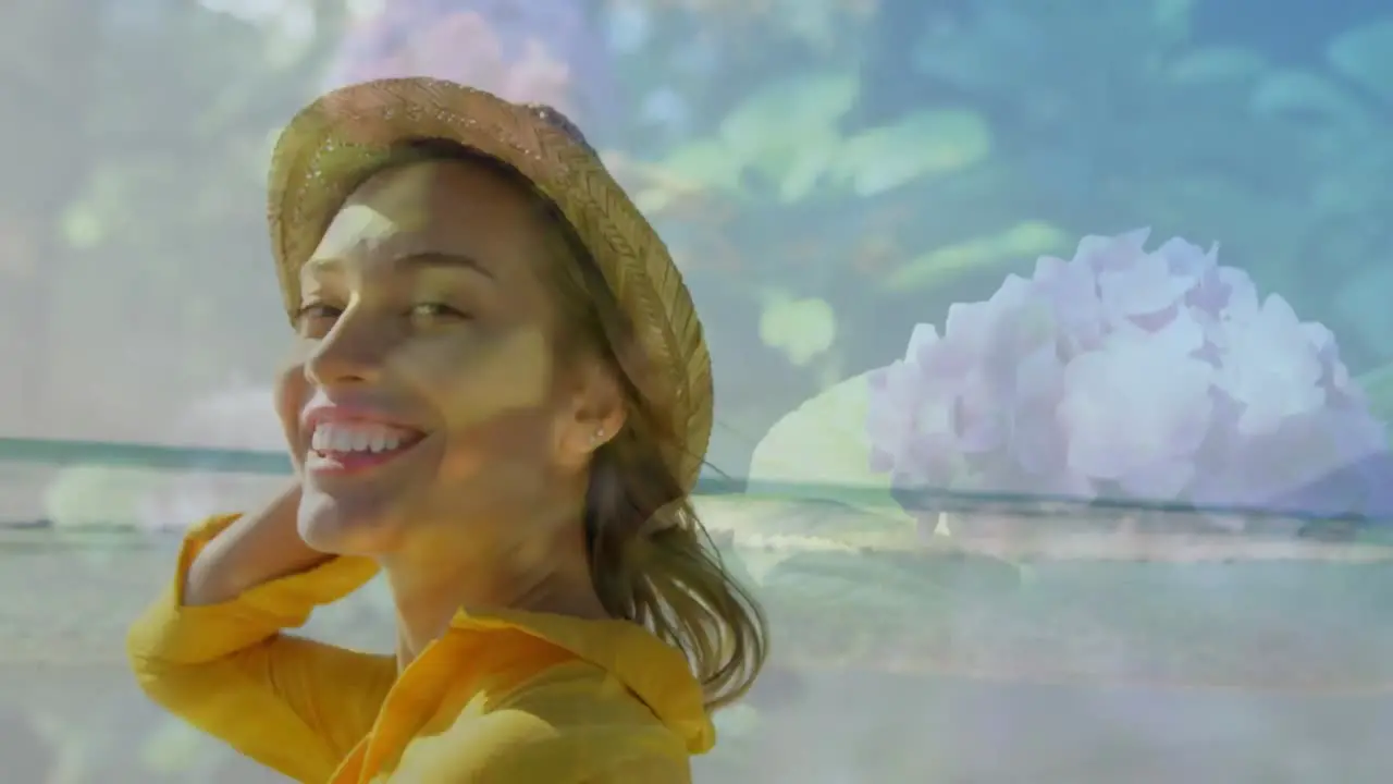 Composite video of portrait of caucasian woman wearing a hat smiling against flower in the garden