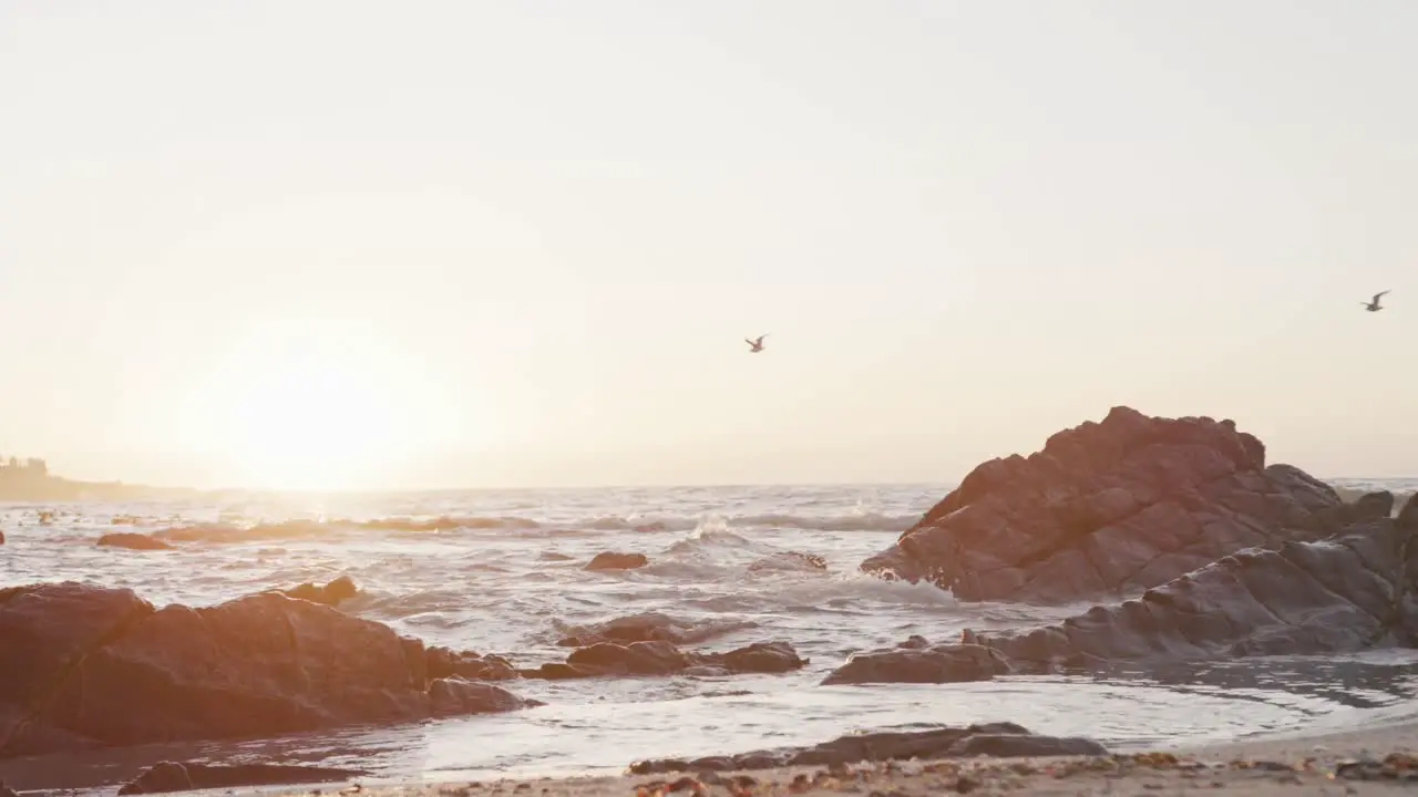 Beach landscape with sea rocks and blue sky at sundown in slow motion