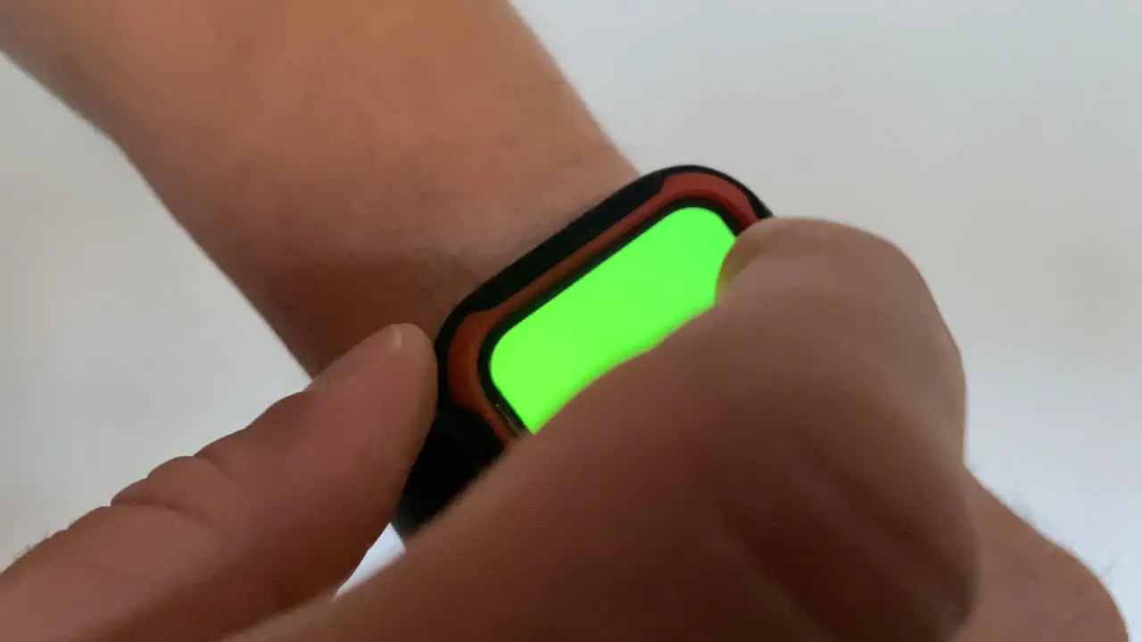 A man uses a smart watch with a chromakey on a green screen and touch him