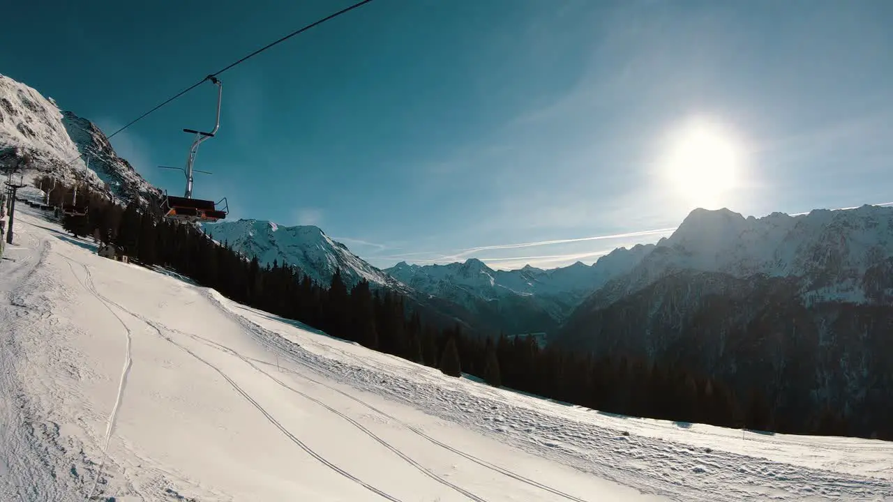 old chair lift above a sunny valley with a lake and mountains on the horizon in slow motion