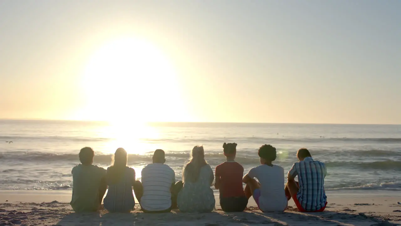 Diverse group of friends enjoy a serene beach sunset with copy space