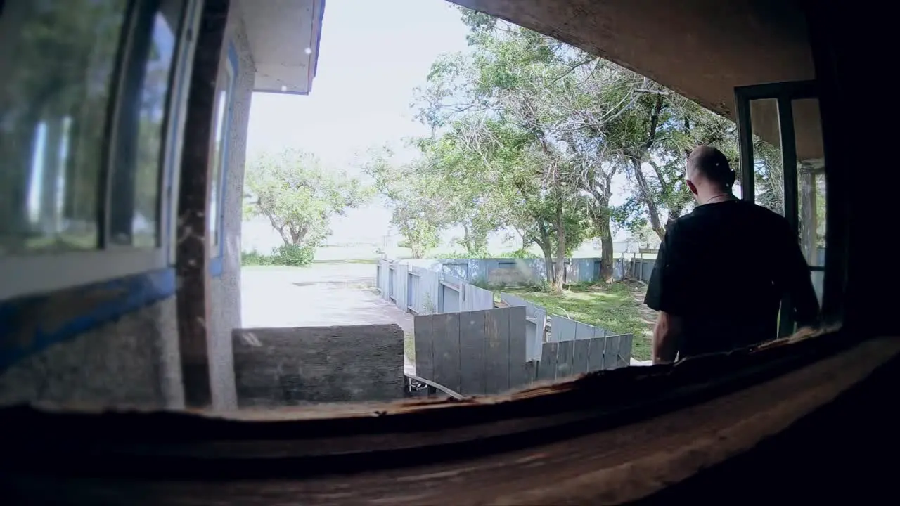 SLOW MOTION View from inside a house looking outside at a bald man leaving the home