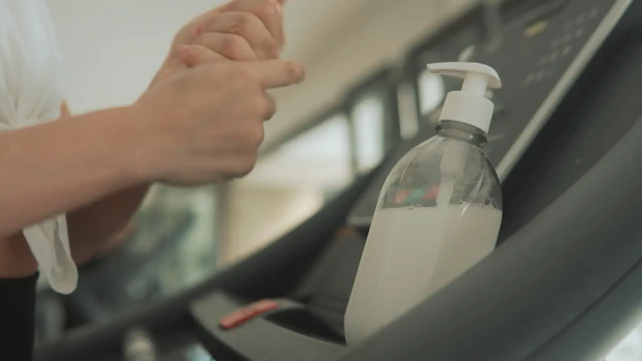 Close Up Hands Using Hand Sanitizer And Exercise Machines In The Gym