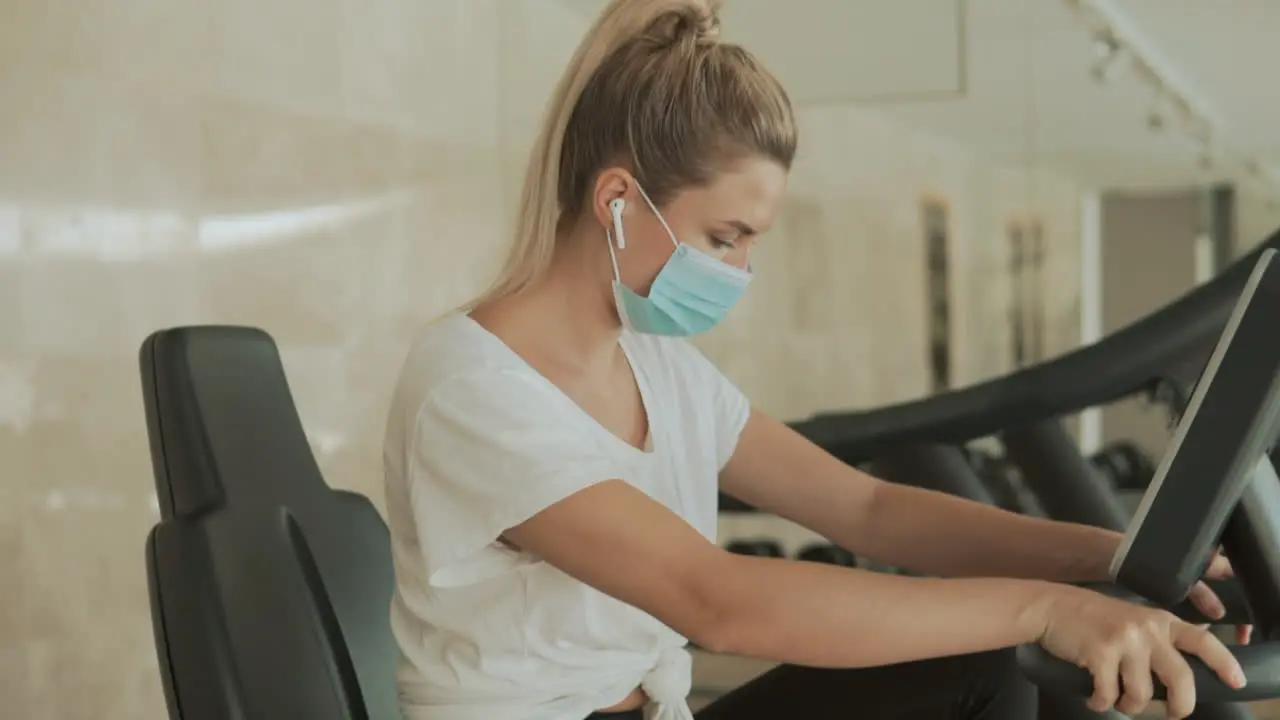 Young Athlete Female With Face Mask Working Out With An Exercise Machine In The Gym