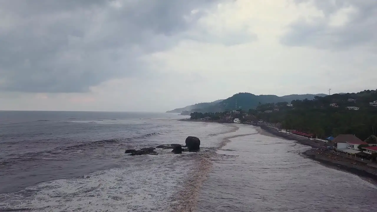 Popular surf spot El Tunco beach in El Salvador during an overcast and cloudy day Aerial footage Dolly out