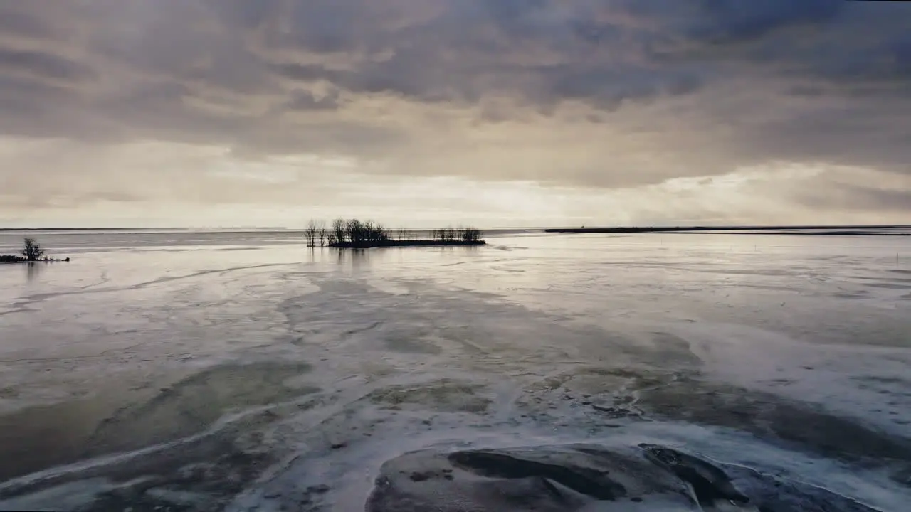 A drone shot flying towards island in the middle of lake Eire which is fronzen