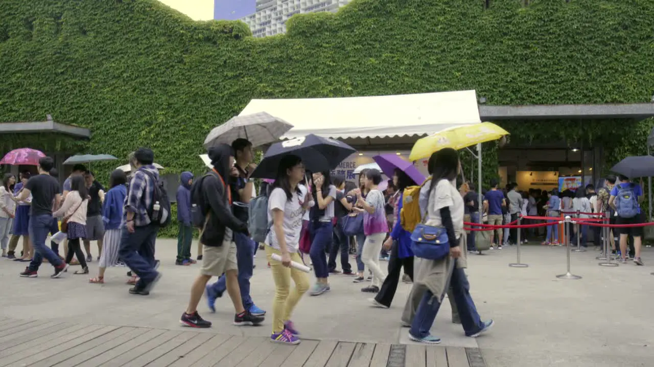 Asian people holding umbrellas and walking around in public space