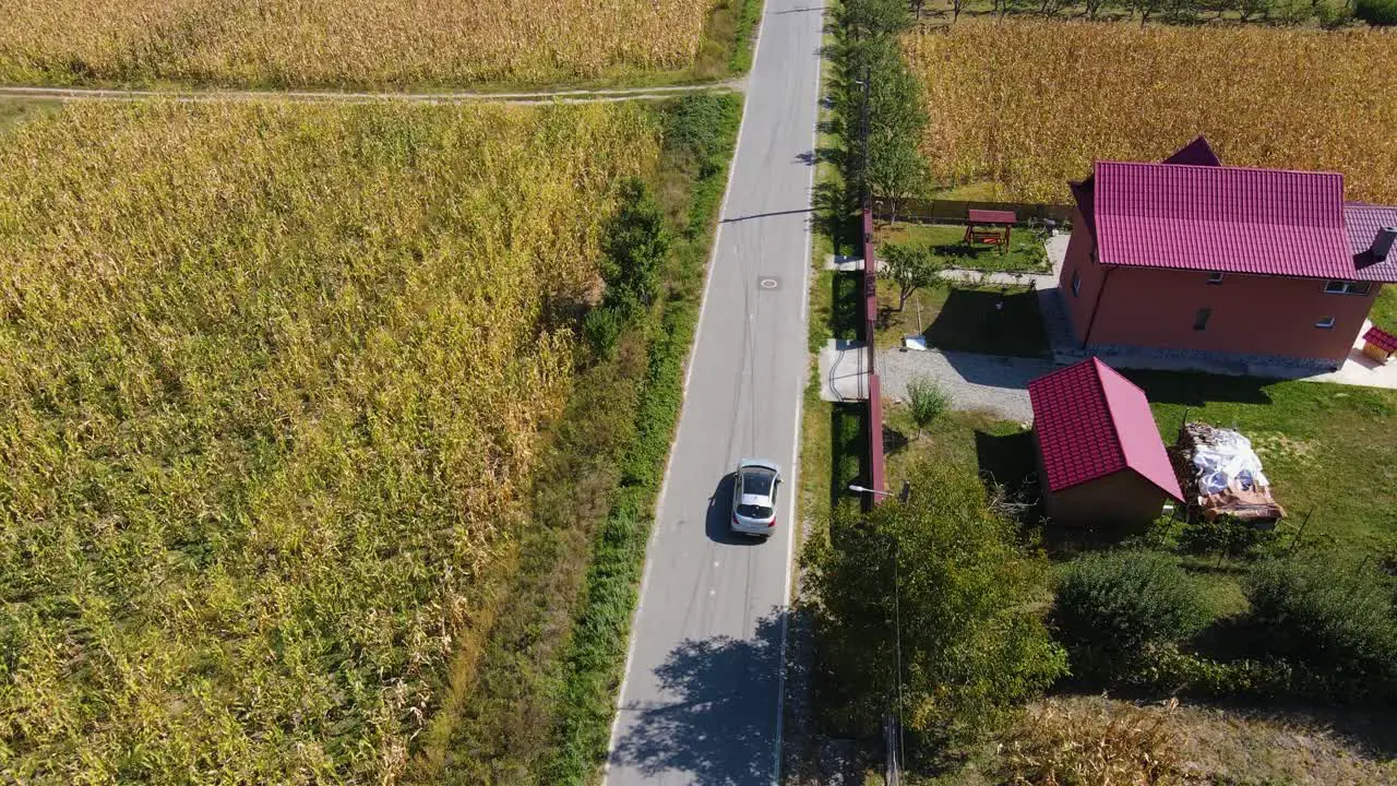 4k Drone silver car chase through a village single street with no cars