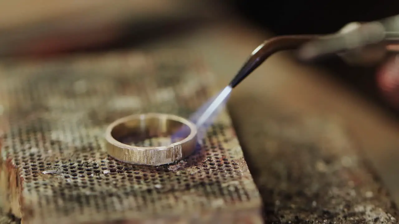 Close up of shaping ring with blowtorch in workshop in slow motion