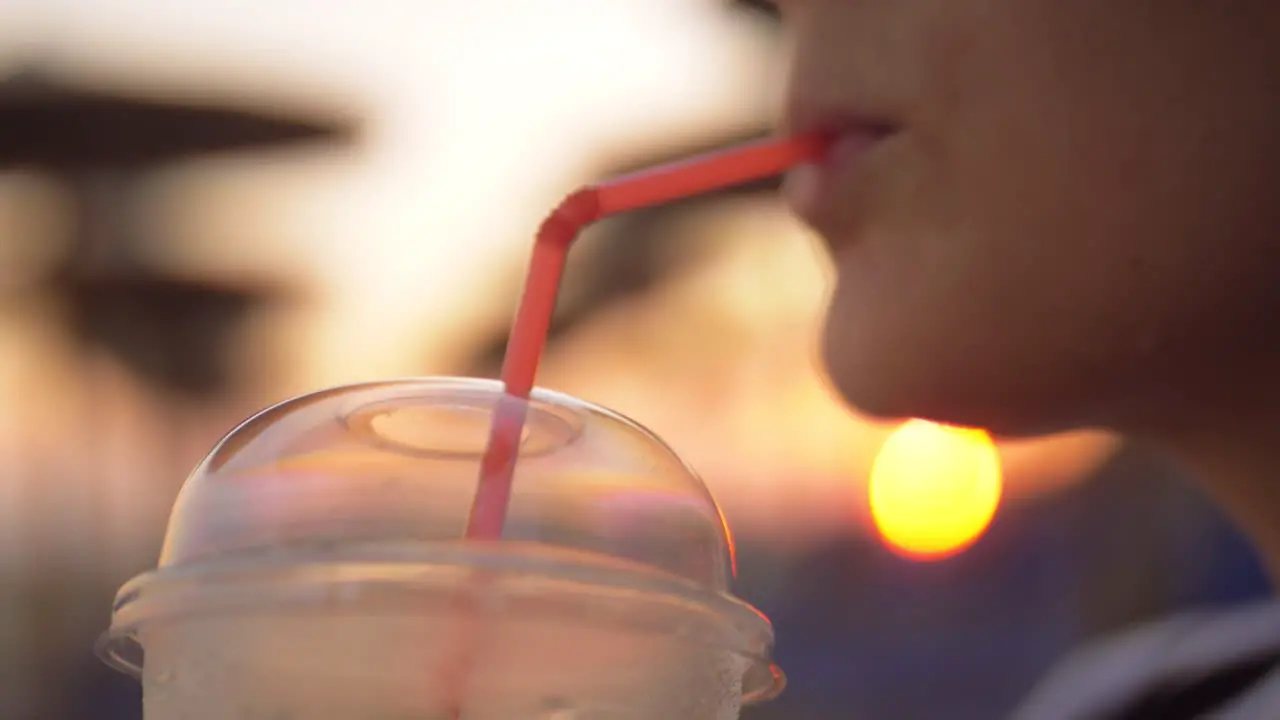 Woman enjoying iced drink outdoor at sunset