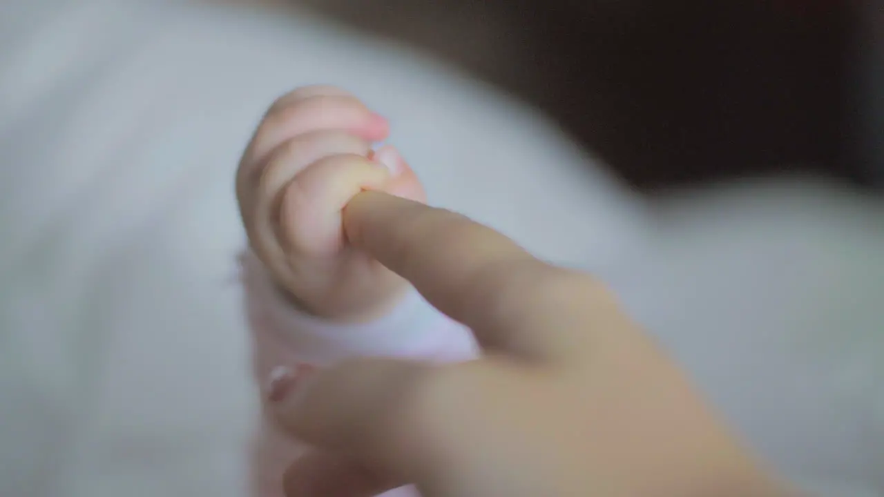 Baby daughter holding mum finger