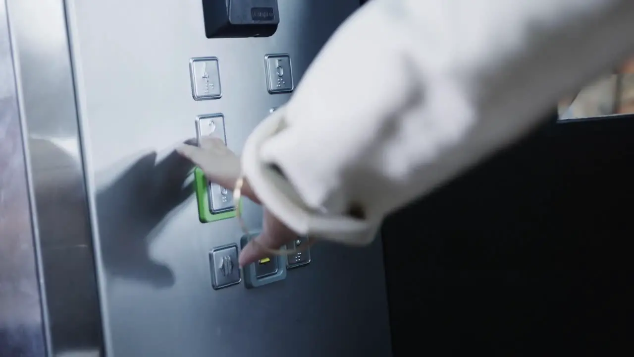 Midsection of biracial businesswoman using elevator in office slow motion