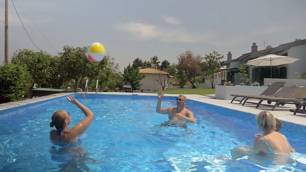 Family playing with a ball in the pool