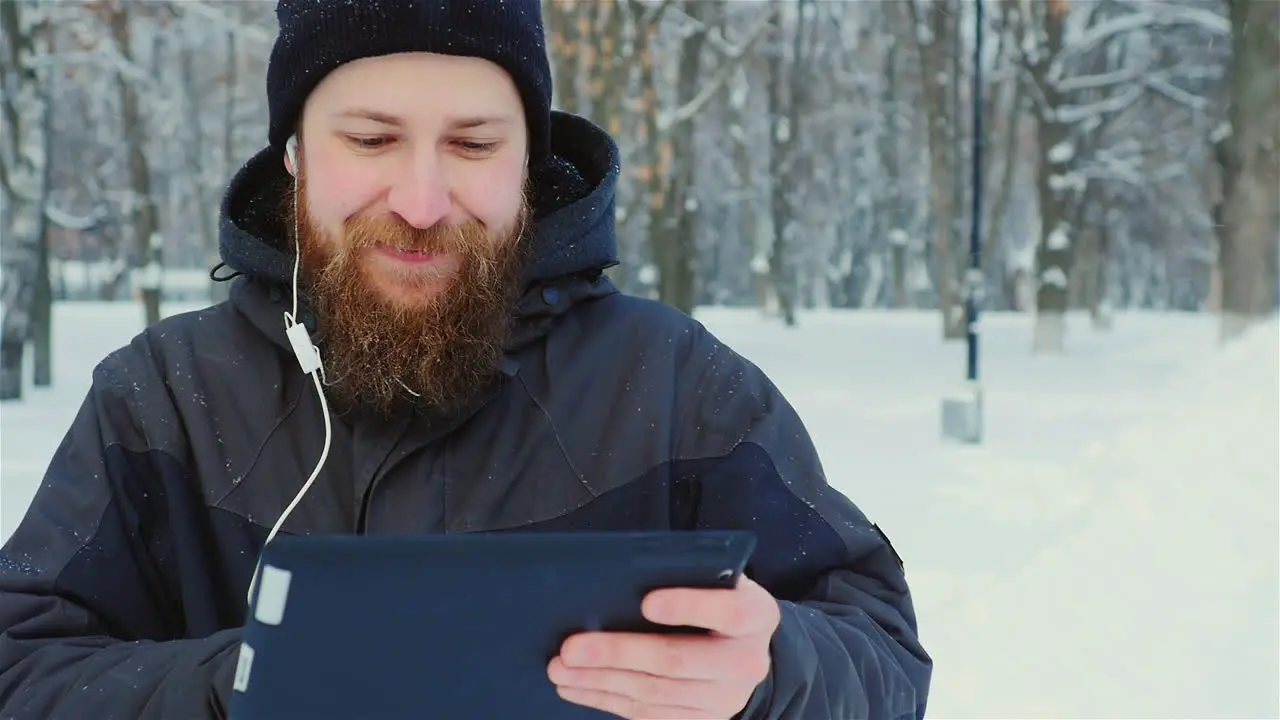 Smiling Man Uses Tablet In Winter Park 01