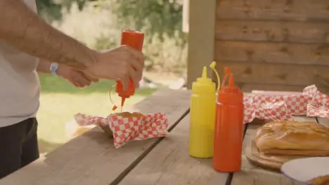 Medium Shot of a Festival Goer Adding Some Sauce to a Hot Dog