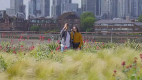 Wide Shot of Two Friends Walking and Taking Selfie Agaisnt London Skyline