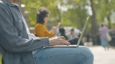 Close Up Shot of a Man Using Laptop Sitting on Park Bench