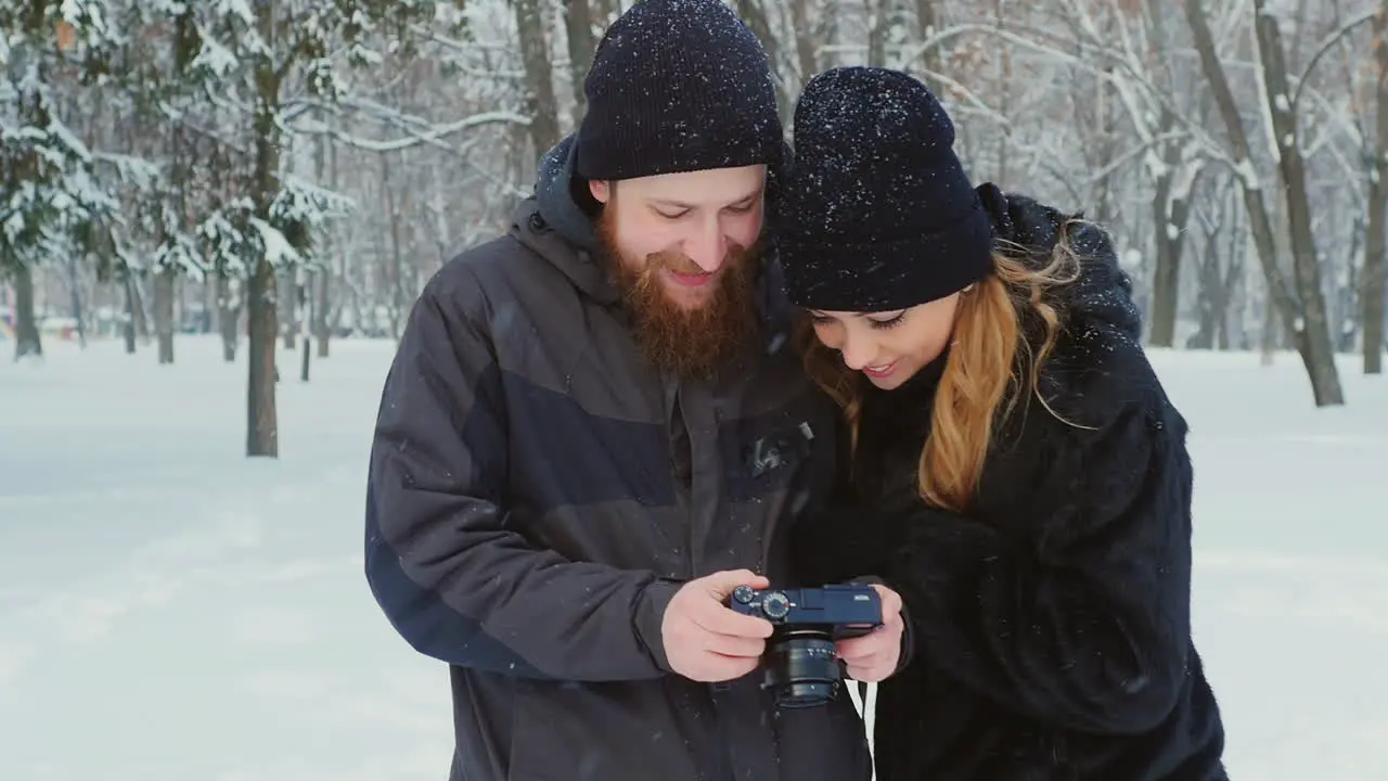 Young Couple Viewing Photos On Camera In Winter