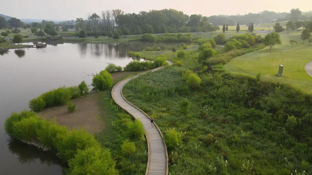 Female jogging alongside a fishing pond at sunrise