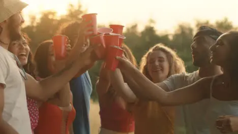 Medium Shot of a Group of Friends Toasting Their Plastic Beer Cups at Sunset