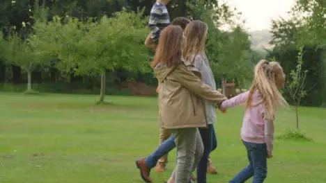 Handheld Shot of Family Walking Through Gardens Talking and Laughing 