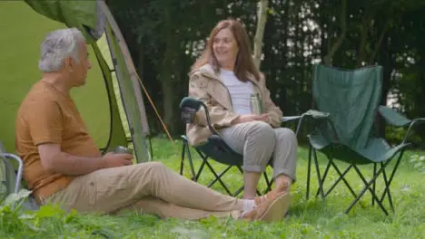 Low Angle Shot of Senior Couple Sitting by Their Tents