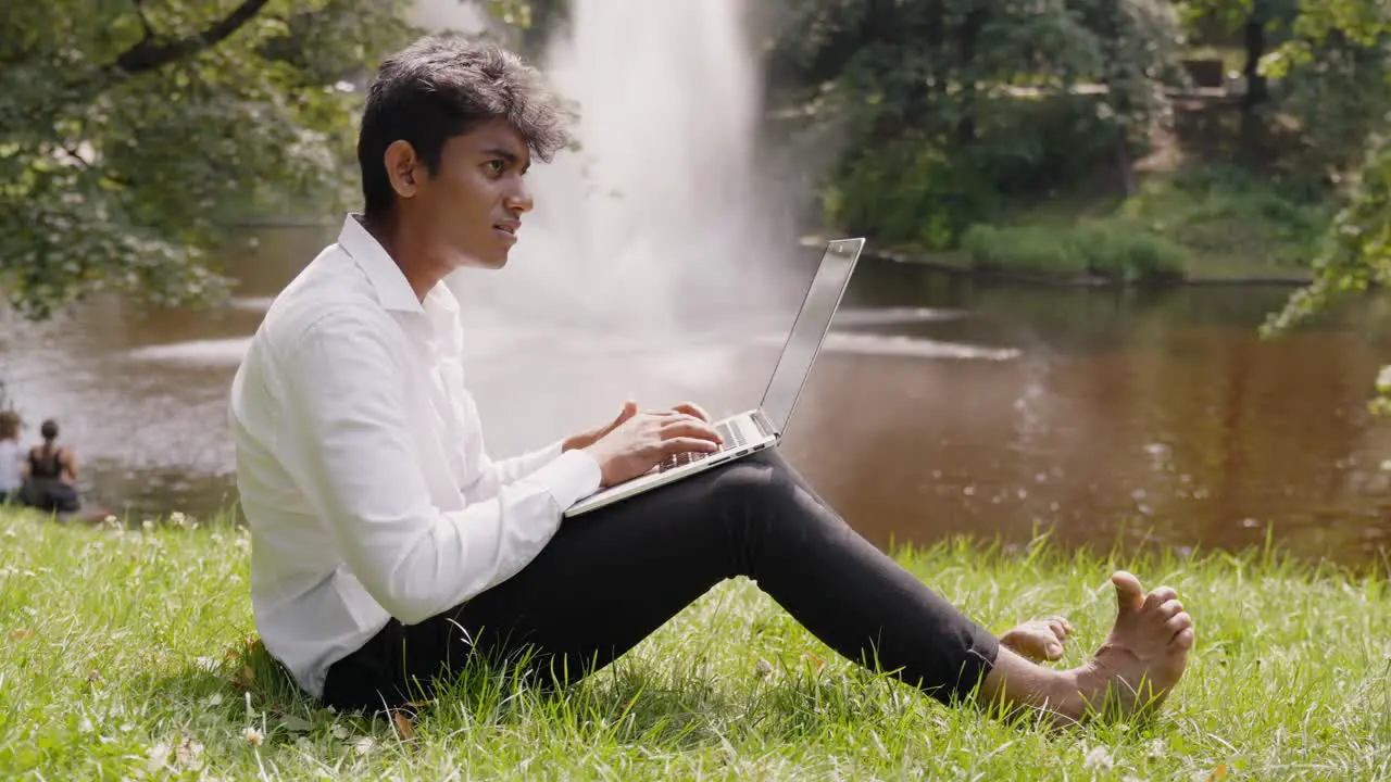 Indian businessman working remotely from park with fountain