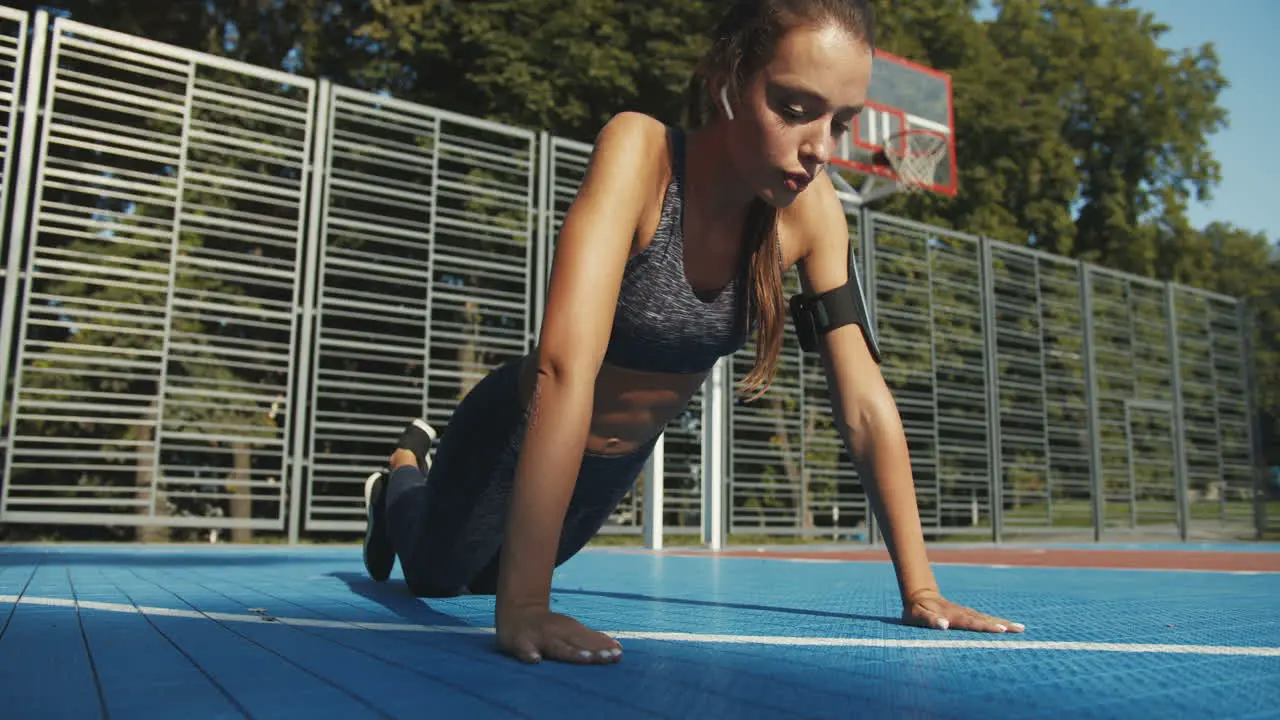 Focused Fitness Girl With Airpods Doing Push Ups At Sport Court On Summer Day