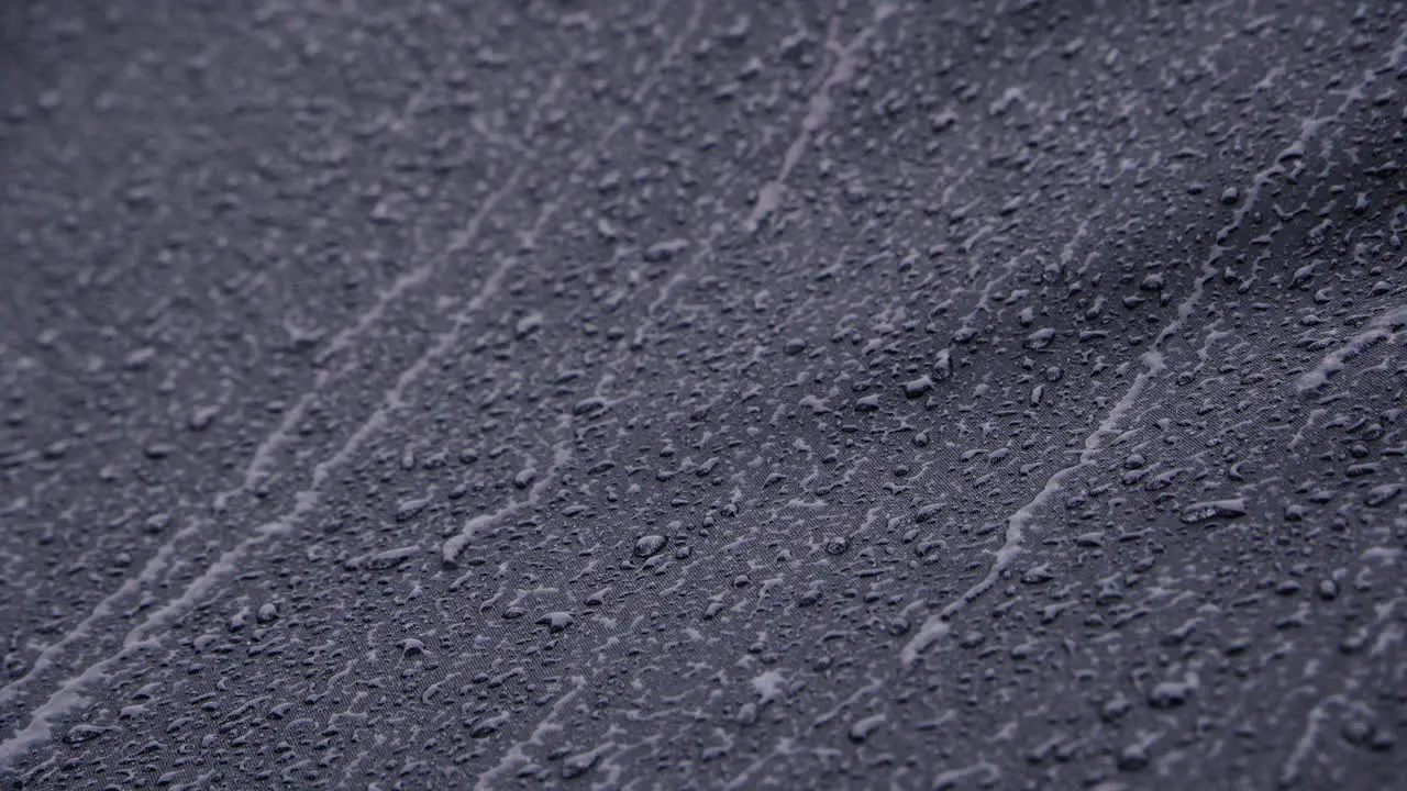 Heavy rain running down on black waterproof textile