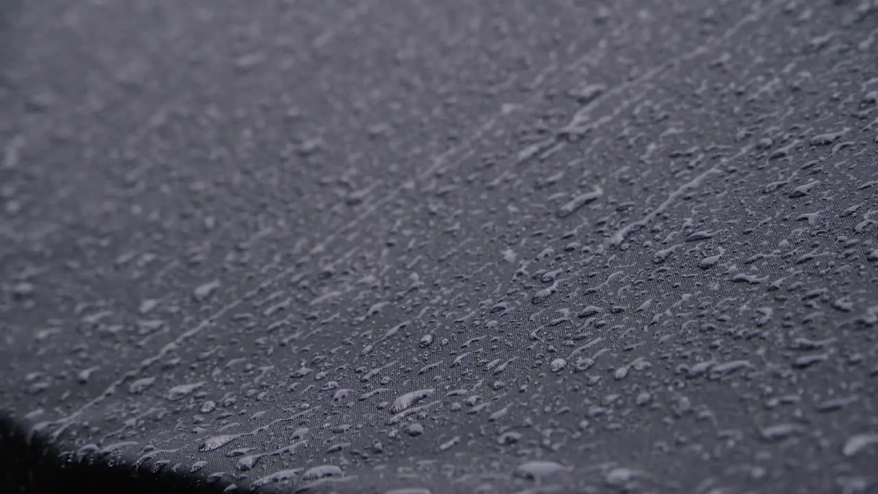 Heavy rain on black waterproof textile 4K