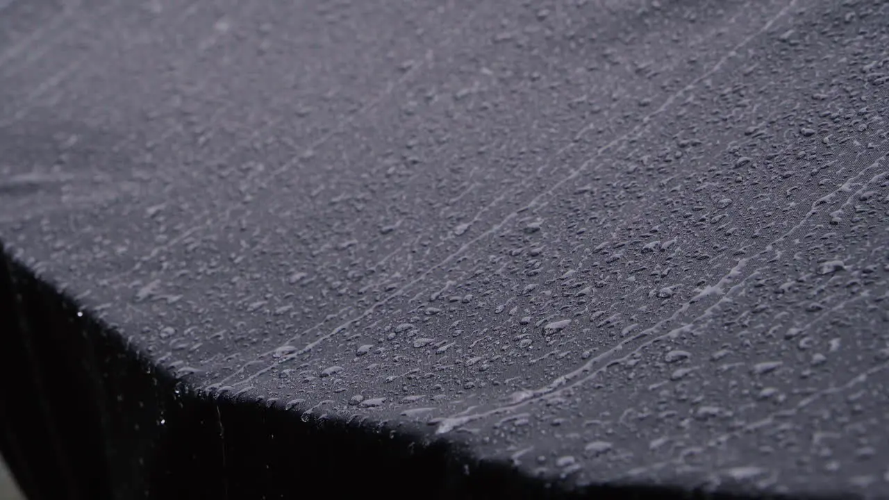 Heavy rain dripping from black waterproof textile 4K