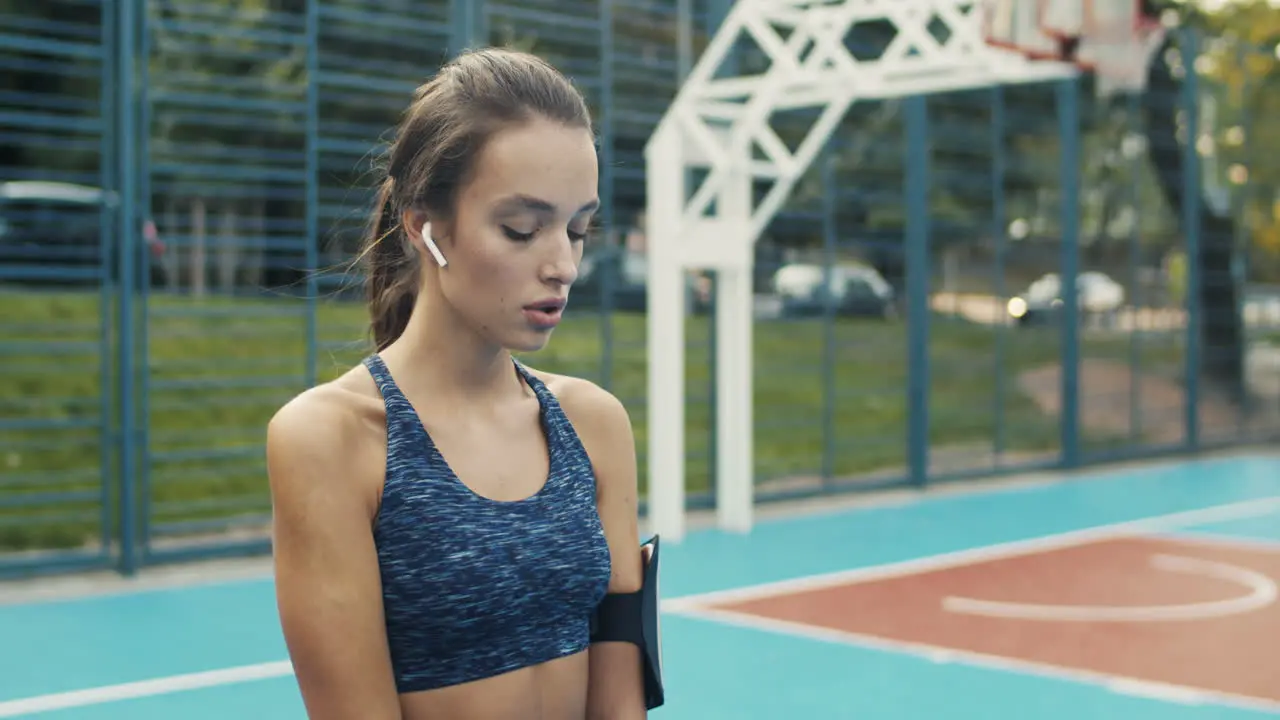 Fitness Girl With Airpods Doing Squats At Sport Court On A Summer Day