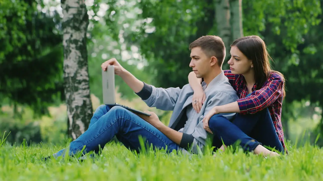 Before Working On The Laptop The Man Opens The Screen Of A Laptop Sitting On The Grass In The Park W