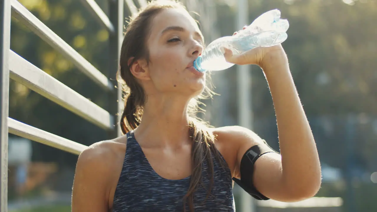 Tired Sporty Woman Standing At An Outdoor Court Resting And Drinking Cold Water After Workout 1