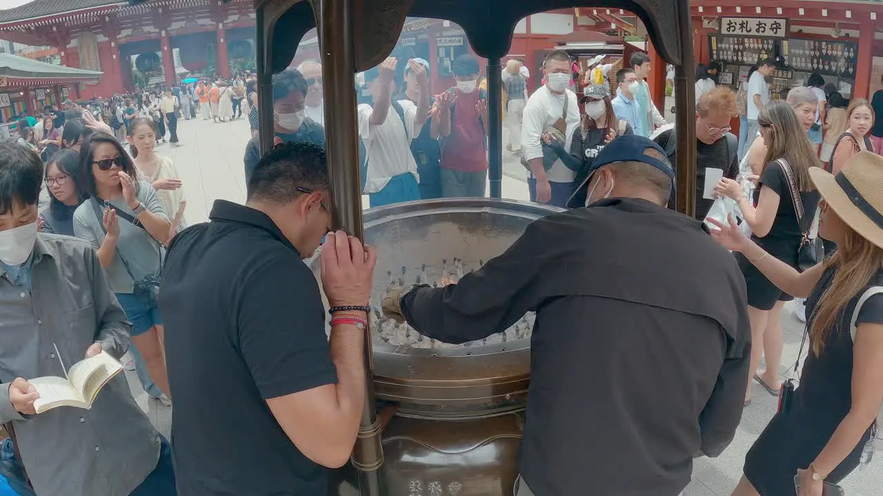 People burning incense at the Senso-ji Buddhist temple in Tokyo Japan