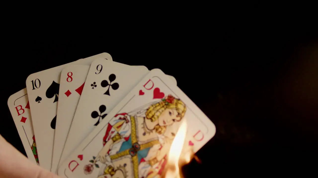 Playing cards held in one hand are burned